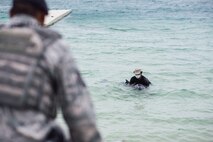 U.S. Air Force retired Master Sgt. David Lacar gently holds onto a dwarf sperm whale April 17, 2017, as an 18th Security Forces team member secures the area at Kadena Marina, Japan. Lacar guided the injured whale off of the rocks at the marina and into deeper water while protecting the whale until help could arrive. (U.S. Air Force photo by Senior Airman Omari Bernard/Released)