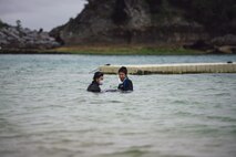 An Okinawan veterinarian inspects the wounds of an injured dwarf sperm whale while a diver from the 18th Force Support Squadron provides support April 17, 2017, at the Kadena Marina, Japan. Okinawan veterinarians worked sided-by-side with personnel from Kadena Air Base to save the whale’s life. (U.S. Air Force photo by Senior Airman Omari Bernard/Released)