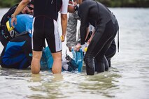 A makeshift rescue team of Okinawan veterinarians, bystanders, and personnel from the 18th Security Forces Squadron and 18th Force Support Squadron place an injured dwarf sperm whale onto a stretcher April 17, 2017, at Kadena Marina, Japan. The team moved quickly and carefully to avoid further injury to the whale. (U.S. Air Force photo by Senior Airman Omari Bernard/Released)