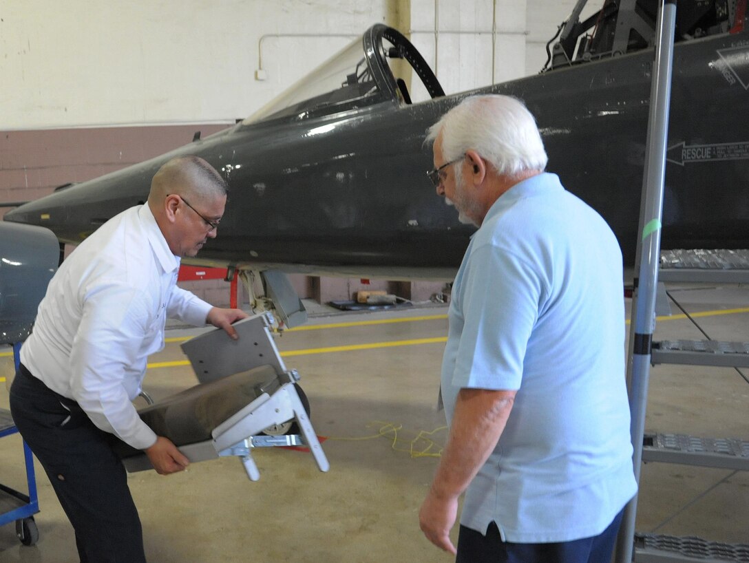 Jimmy Pulido, left, 12th Flying Training Wing maintenance egress supervisor and Michael LoBue, egress technician, prepare to install a foldable seat on a T-38 aircraft, April 17, 2017. 