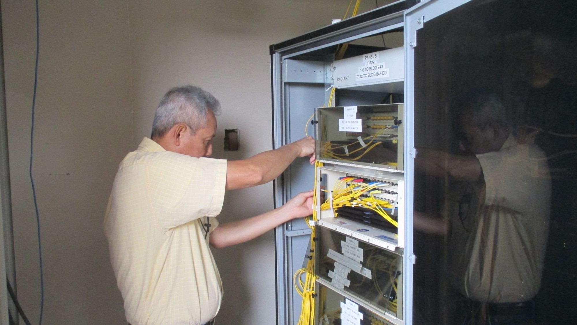 An engineer with the 38th Cyberspace Engineering Installation Group pulls wires on a core node March 28, 2017, at Kadena Air Base, Japan. Members of the 38th CEIG visited Kadena and worked with the Airmen of the 18th Communications Squadron to identify outdated systems and assist in updating them. (Courtesy photo)
