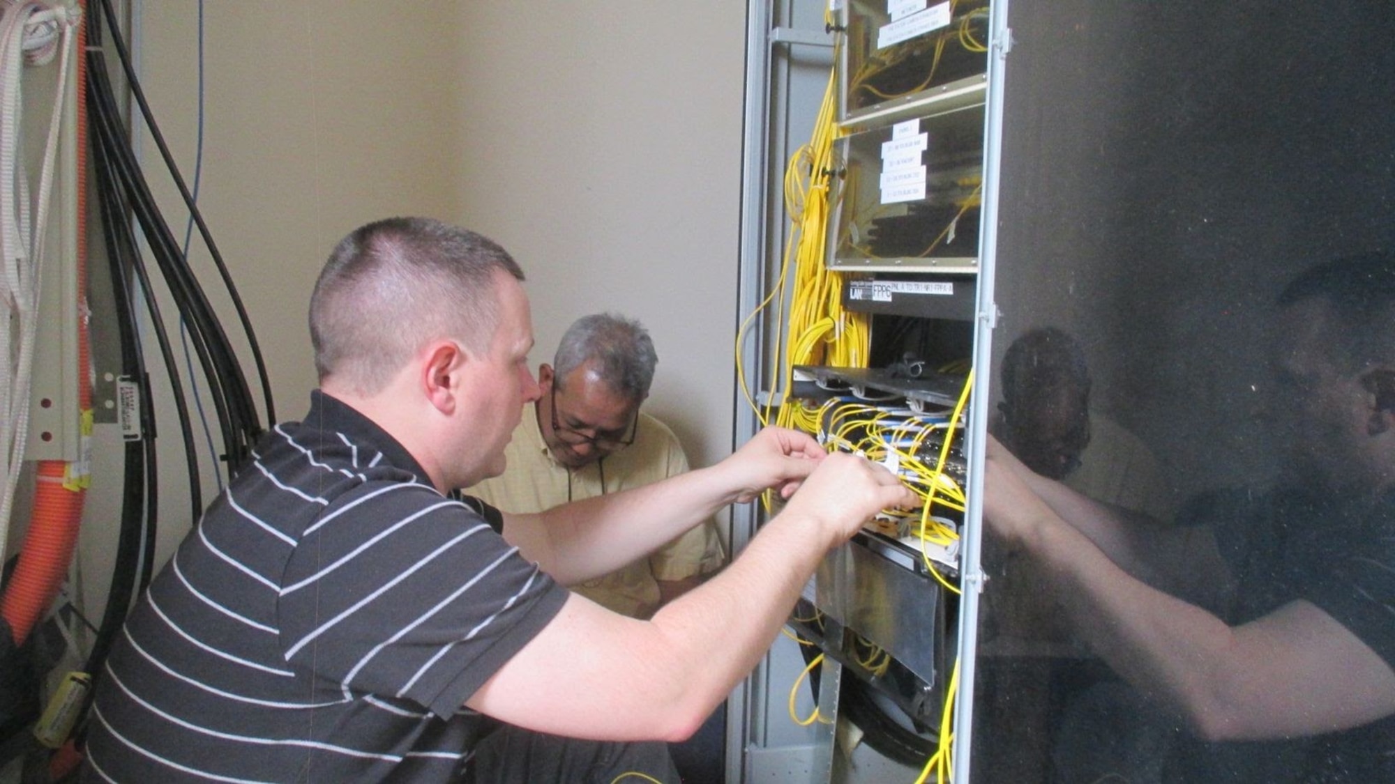 Members of the 38th Cyberspace Engineering Installation Group work together to identify wire locations on a core node March 28, 2017, at Kadena Air Base, Japan. Reducing the number of routers was the primary focus of the 38th CEIG during their month-long temporary assignment to Kadena. The reduction is estimated to save the 18th Communications Squadron more than 100 man hours of maintenance each year. (Courtesy photo)