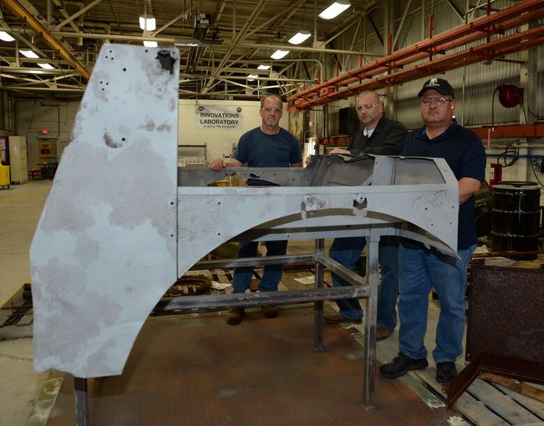 From left are David Tucker, heavy mobile equipment mechanic; Jody Nesbitt, project officer and Robert Guzman, planner estimator; all with Marine Depot Maintenance Command, as they pose April 17 with the cab of a World War II, Suspension Unit-Cab Over Engine Prime Mover, 4x4 Cargo Truck, which is being restored for the National Museum of the Marine Corps.