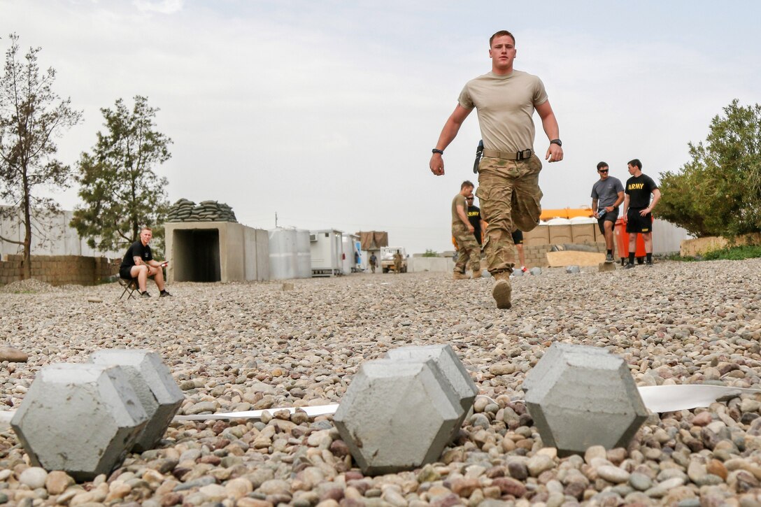 Army Pfc. Christian Root sprints to pick up dumbbells during the farmer’s carry relay, as part of a strongman competition held at a tactical assembly area near Bakhira, Iraq, April 12, 2017. Root is assigned to the 82nd Airborne Division’s 2nd Brigade Combat Team. Army photo by Staff Sgt. Jason Hull