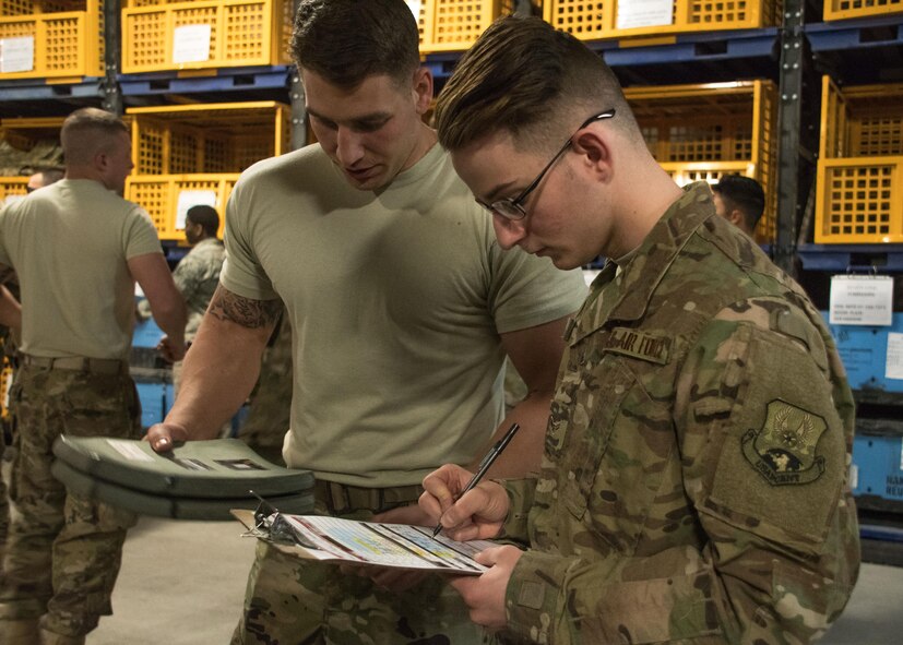 Airman 1st Class Brent Downs, a 386th Expeditionary Logistics Readiness Squadron distribution journeyman, left, issues an improved outer tactical vest to Airman 1st Class Alex Gardner, a traffic management office journeyman, at an undisclosed location in Southwest Asia April 19, 2017. Working at the expeditionary theater distribution center here requires careful attention to detail to ensure forward deployers receive necessary items. (U.S. Air Force photo/Staff Sgt. Andrew Park)