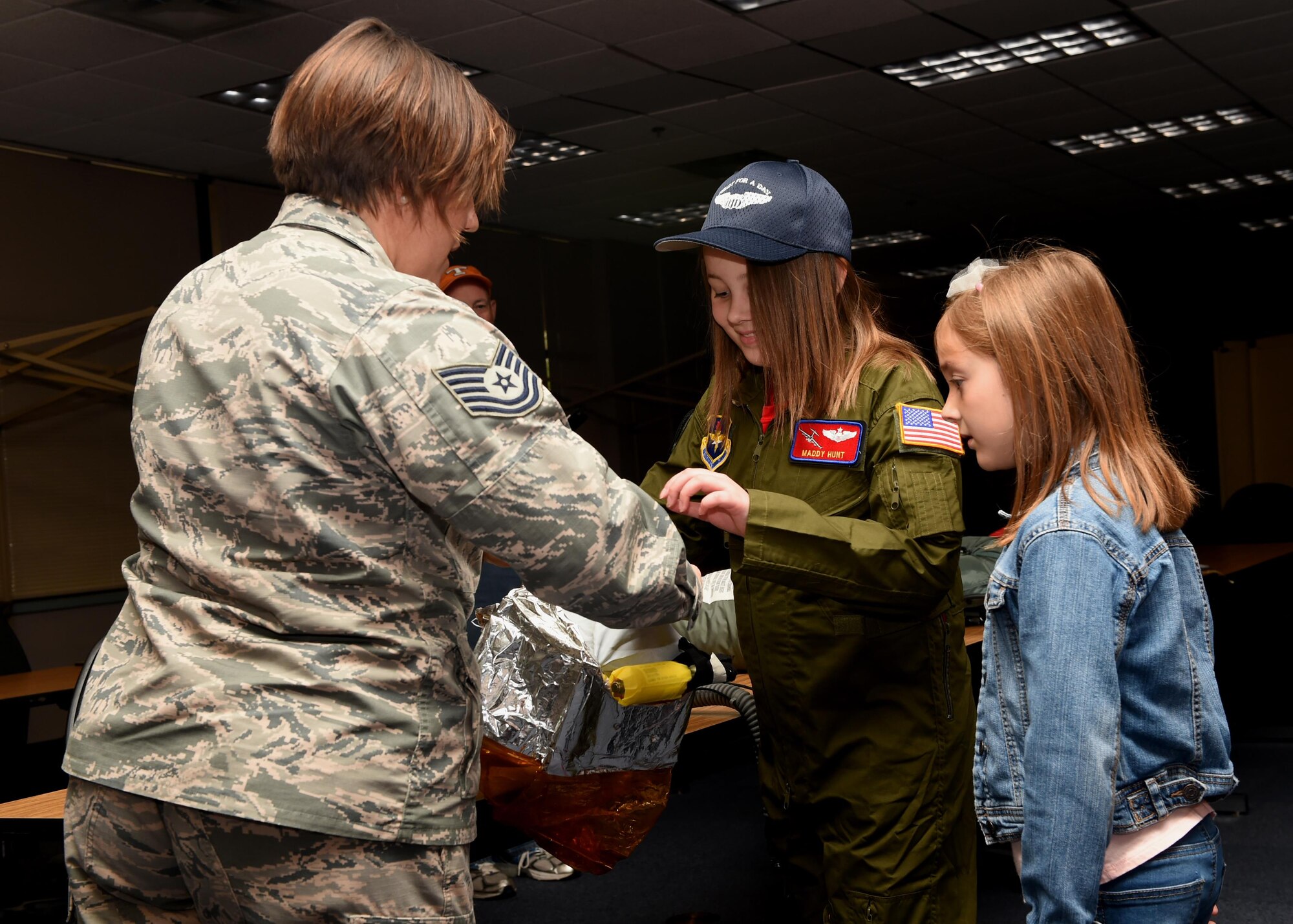 U.S. Air Force Tech. Sgt. Christie Kidder, 97th Operations Support Squadron flight chief of Aircrew Flight Equipment demonstrates how to use an oxygen mask to Maddy Hunt during the Pilot for a Day Program at Altus Air Force Base Oklahoma, April 14, 2017. The Pilot for a Day Program allows a child with a serious illness to tour the base and experience multiple aspects of Air Force life. (U.S. Air Force photo by SrA. Megan E. Myhre/Released)