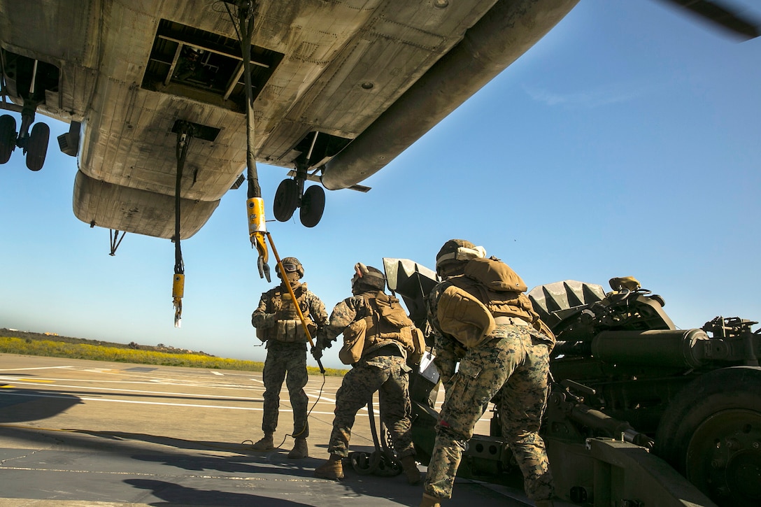 A Marine, left, uses a static discharge wand to discharge excess static electricity before attaching an M777 howitzer to a CH-53E Super Stallion helicopter during integrated slingload training at Marine Corps Base Camp Pendleton, Calif., April 12, 2017. Marine Corps photo by Cpl. Frank Cordoba