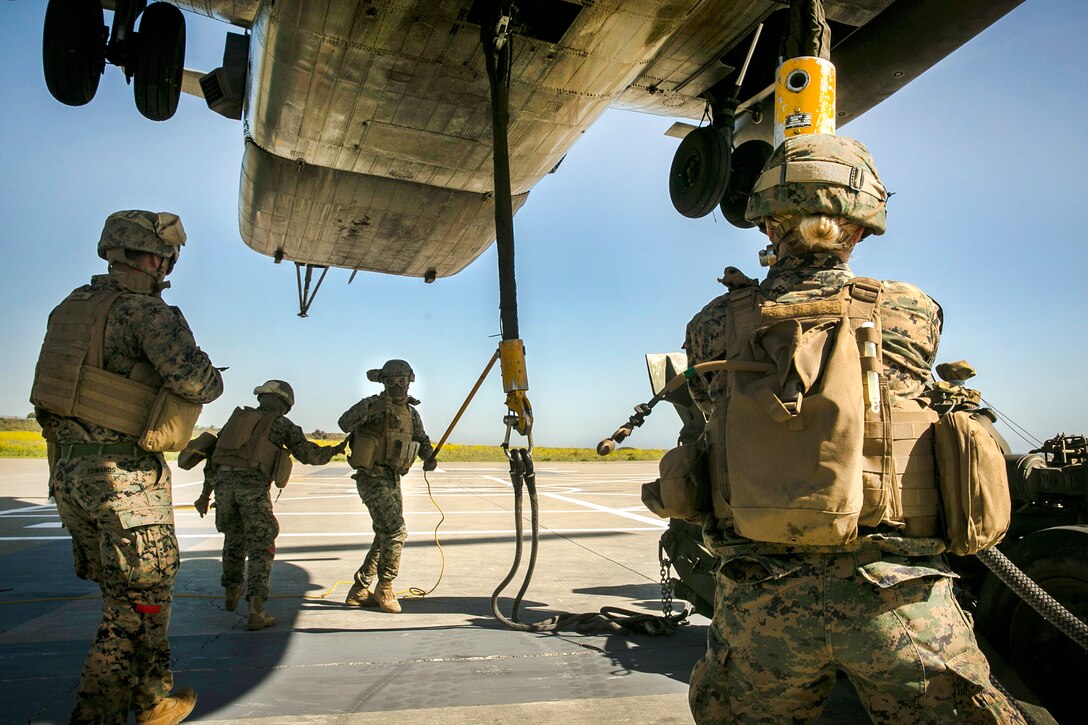 A Marine, center, uses a static discharge wand to discharge excess static electricity before a hookup team attaches an M777 howitzer to a CH-53E Super Stallion helicopter during integrated slingload training at Marine Corps Base Camp Pendleton, Calif., April 12, 2017. Marine Corps photo by Cpl. Frank Cordoba