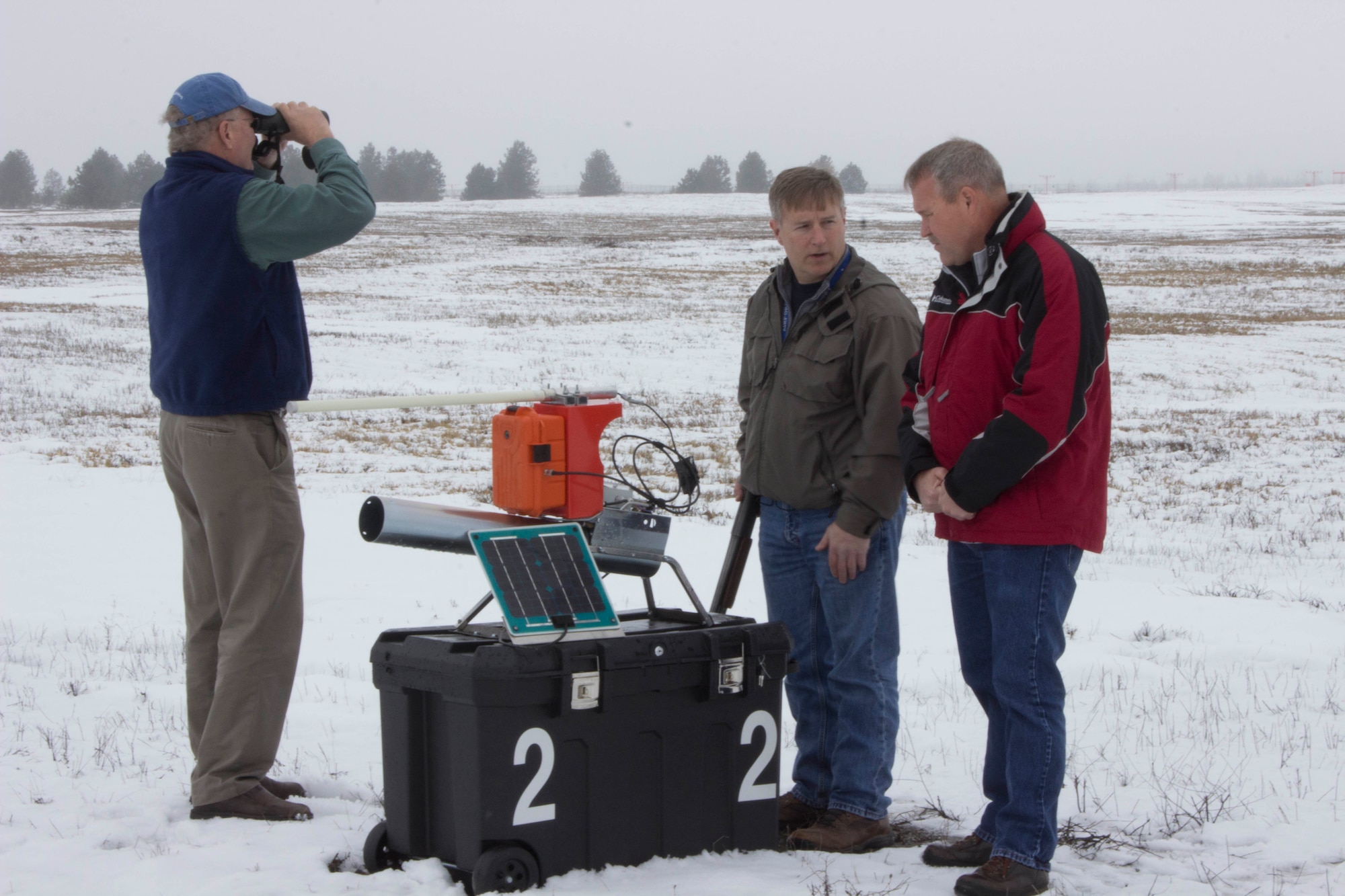 From left, Kevin Porteck, AFCEC natural resources subject matter expert, looks for birds while Dan Paulus, center, pest management foreman for Fairchild Air Force Base, Washington, and Don Teig, AFCEC entomologist and subject matter expert, discuss the usage of the propane air cannon for bird deterrence on the airfield at the base March 9, 2017. (U.S. Air Force photo/Susan Lawson).