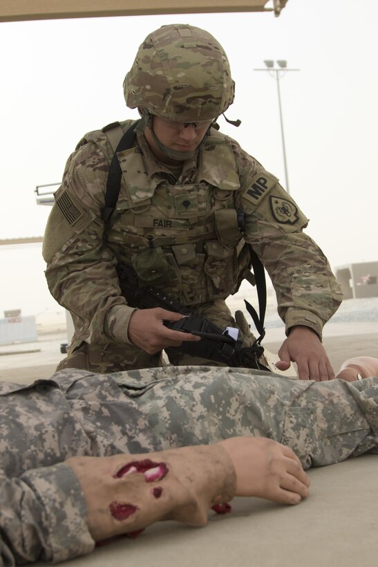 Spc. David Fair, with the 485th Military Police Company, applies a tourniquet to a dummy during the 1st Sustainment Command (Theater) Best Warrior Competition Combat Life Saver exam at Camp Arifjan, Kuwait, April 15, 2017. (U.S. Army Photo by Staff Sgt. Dalton Smith)