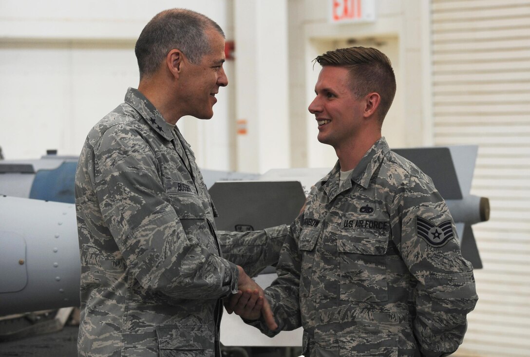 U.S. Air Force Staff Sgt. Vaughn Turnbow, 7th Munitions Squadron conventional maintenance supervisor, is coined by Maj. Gen. Thomas Bussiere, 8th Air Force commander, at Dyess Air Force Base, April 18, 2017. During his three-day trip, Bussiere went to several squadrons to personally thank and award Airmen for their hard work and dedication to the Dyess mission. (U.S. Air Force photo by Airman Kylee Thomas)