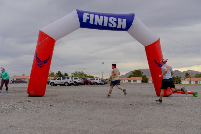 Airmen cross the finish line at the 5k Color Run/Walk, April 7, 2017, at Nellis Air Force Base, Nev. Multiple base agencies set up stands at the finish line to promote awareness and offer further information for Airmen and their families. (U.S. Air Force photo by Airman 1st Class Andrew D. Sarver/ Released)

