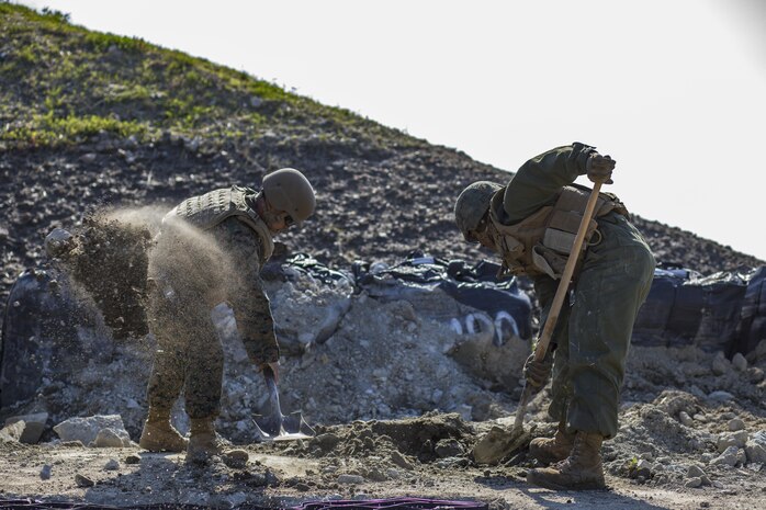 U.S. Marine Corps Gunnery Sgt. Myron Sato, left, the combat engineer staff noncommissioned officer in charge for Marine Wing Support Squadron (MWSS) 171, and Pfc. Jason Taylor, right a combat engineer with MWSS-171, shovel dirt and mud during airfield damage and repair training at Marine Corps Air Station Iwakuni, Japan, April 19, 2017. The ADR training required Marines to utilize their skill set to tactically and proficiently fix any anomalies to a simulated damaged airfield. The training focused on becoming more efficient in situations that may require Marines to act in real-world scenarios to maintain the tempo of aircraft operations. (U.S. Marine Corps photo by Lance Cpl. Joseph Abrego)