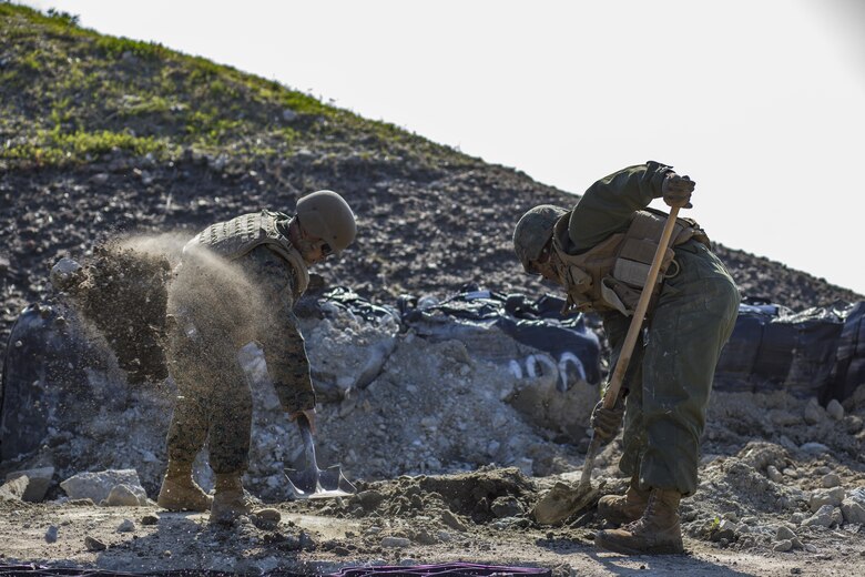 U.S. Marine Corps Gunnery Sgt. Myron Sato, left, the combat engineer staff noncommissioned officer in charge for Marine Wing Support Squadron (MWSS) 171, and Pfc. Jason Taylor, right a combat engineer with MWSS-171, shovel dirt and mud during airfield damage and repair training at Marine Corps Air Station Iwakuni, Japan, April 19, 2017. The ADR training required Marines to utilize their skill set to tactically and proficiently fix any anomalies to a simulated damaged airfield. The training focused on becoming more efficient in situations that may require Marines to act in real-world scenarios to maintain the tempo of aircraft operations. (U.S. Marine Corps photo by Lance Cpl. Joseph Abrego)