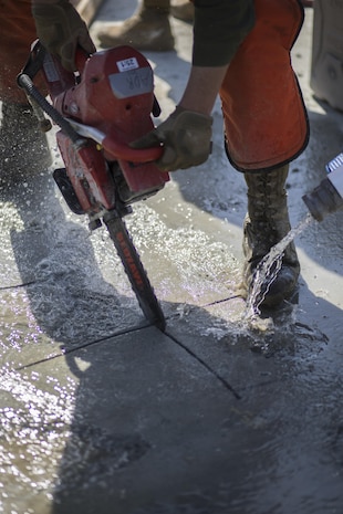 Water cools a chainsaw as it cuts through concrete during airfield damage and repair training at Marine Corps Air Station Iwakuni, Japan, April 19, 2017. The ADR training required Marines to utilize their skill set to tactically and proficiently fix any anomalies to a simulated damaged airfield. The training focused on becoming more efficient in situations that may require Marines to act in real-world scenarios to maintain the tempo of aircraft operations. (U.S. Marine Corps photo by Lance Cpl. Joseph Abrego)
