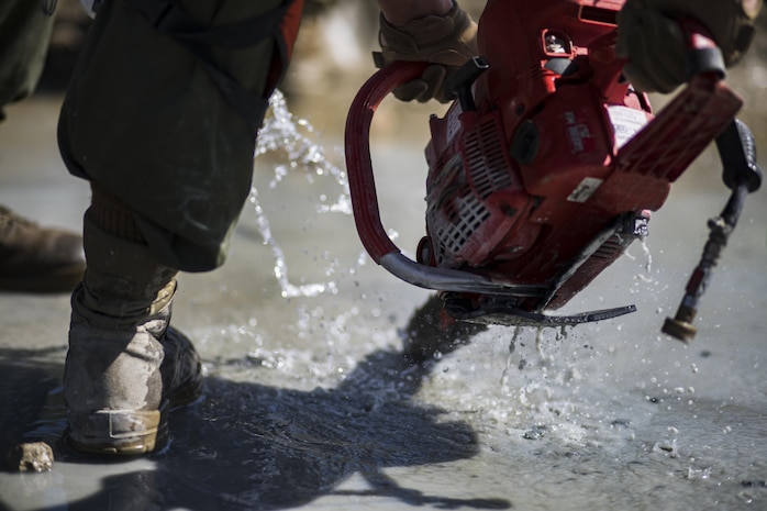 Water cools a chainsaw as it cuts through concrete during airfield damage and repair training at Marine Corps Air Station Iwakuni, Japan, April 19, 2017. The ADR training required Marines to utilize their skill set to tactically and proficiently fix any anomalies to a simulated damaged airfield. The training focused on becoming more efficient in situations that may require Marines to act in real-world scenarios to maintain the tempo of aircraft operations. (U.S. Marine Corps photo by Lance Cpl. Joseph Abrego)