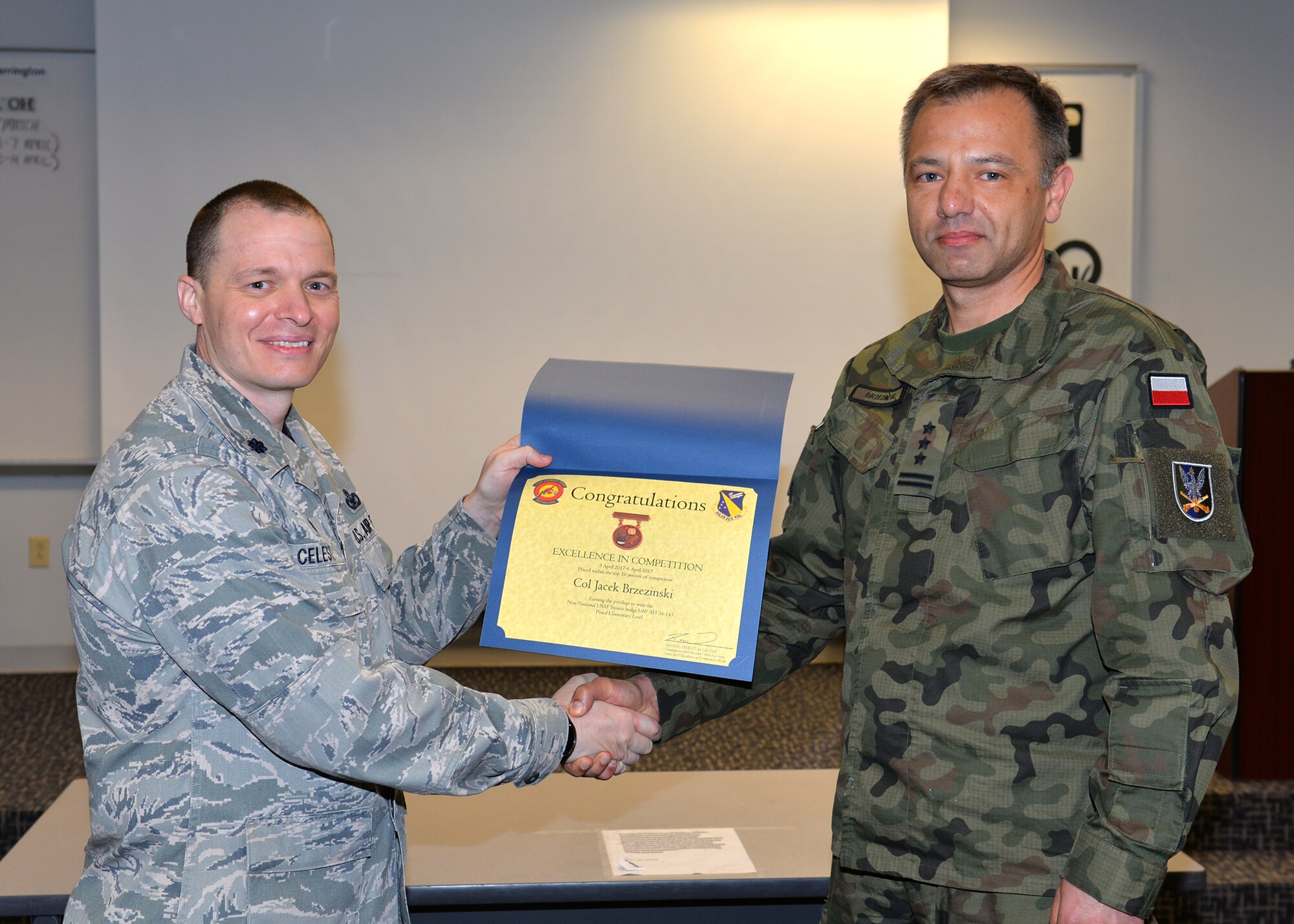 Lt. Col. David Celeste, 88th Security Forces Squadron commander, congratulates and presents a certificate to Polish Air Force Colonel Jacek Brzezinski, Polish liaison to the Air Force Security Assistance Center at Wright Patterson Air Force Base as the first place pistol category finisher in the Excellence in Competition firearms marksmanship contest April 14, 2017. The EIC competition held across all Department of Defense  installations provides military members, civilian employees and retirees the opportunity to refine their marksmanship skills, competing against each other in pursuit of earning marksmanship awards eligible for wear on the uniform or civilian attire. (U.S. Air Force photo/Al Bright)