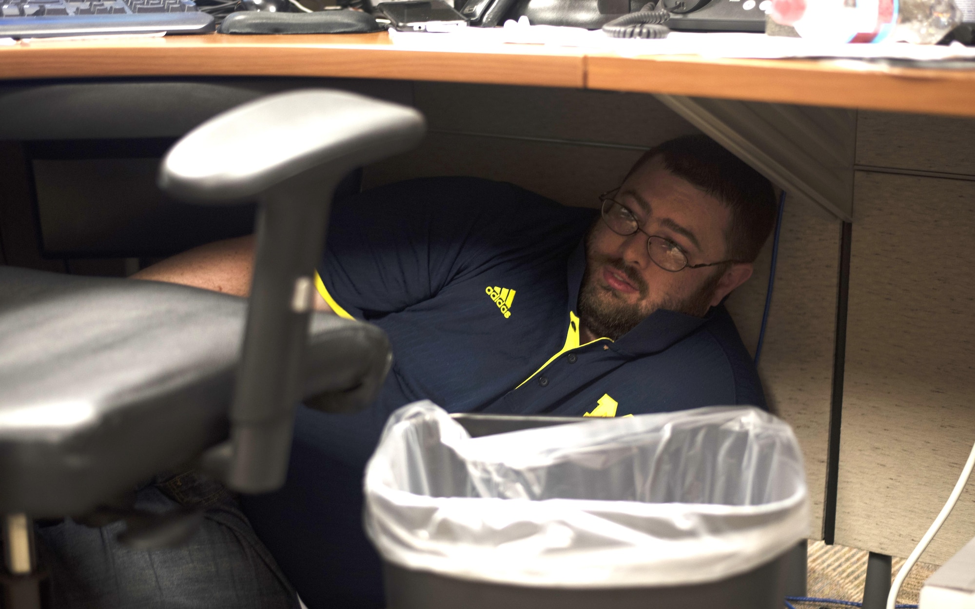 A member of the 927th Air Refueling Wing, hides under his desk after shots were fired during an active shooter exercise at MacDill Air Force Base, Fla., April 17, 2017. During this scenario, service members are advised to seek shelter and barricade themselves in offices to hide from the shooter. (U.S. Air Force photo by Airman 1st Class Adam R. Shanks)
