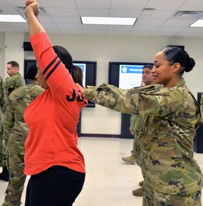 1st Lt. Deborah Edwards, right, a psychiatric nurse at the William Beaumont Army Medical Center, Fort Bliss, Texas, practices a de-escalation and therapeutic containment technique on Ellisha Jones, Family Advocacy Program clinical social worker at Winn Army Community Hospital, Fort Stewart, Ga., during a training session April 13 at the U.S. Army Medical Department Center and School, Joint Base San ANtonio-Fort Sam Houston. During the week-long training, 36 military medical professionals from military treatment facilities throughout the world learned skills in Prevention and Management of Disrupted Behavior-Military that will help them calm and settle down patients in crisis.