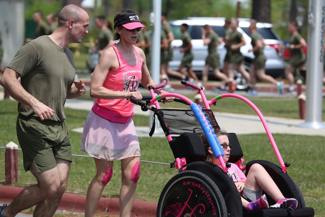 Marines run along side volunteer runners during a formation run at Marine Corps Air Station New River, N.C., April 13, 2017. More than 220 Marines assigned to Marine Aviation Logistics Squadron 26, Marine Aircraft Group 26, 2nd Marine Aircraft Wing  gathered to run with disabled children as part of an Ainsley’s Angels East Carolina chapter event at the air station. Ainsley’s Angels is an organization that focuses on providing children with disabilities the oportunity to be included in runs that range in distances from 5k up to 50k. Volunteers are assigned as angels to push the athlete riders and cross the finish line. ( U.S. Marine Corps photo by Sgt. N.W. Huertas/ Released)