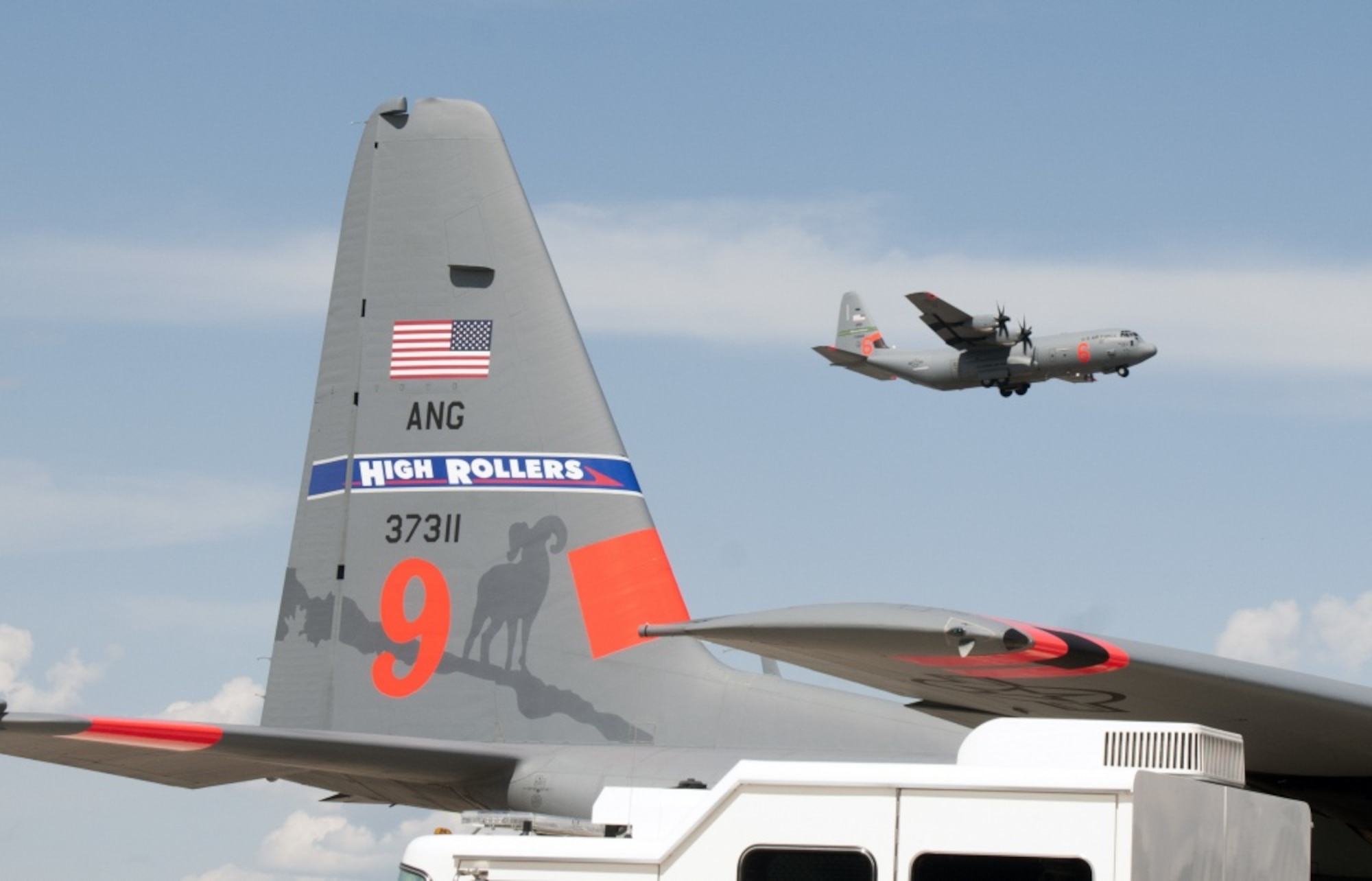 A California Air National Guard C-130 Hercules flies by a Nevada Air National Guard C-130 during this week's Modular Airborne Fire Fighting System training and certification in Boise, Idaho. More than 400 personnel of four C-130 Guard and Reserve units — from California, Colorado, Nevada and Wyoming, making up the Air Expeditionary Group — are in Boise for the week-long wildfire training and certification sponsored by the U.S. Forest Service. (U.S. Air Force photo/Tech. Sgt.  Tech. Sgt. Emerson Marcus)