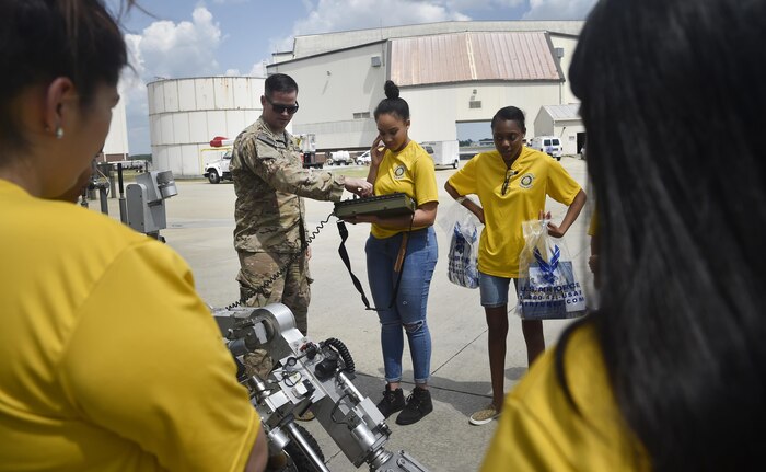 Staff Sgt. Joshua Rickert, center left, 628th Civil Engineer Squadron explosive ordinance, disposal, shows Destiny Linen, center right, Junior Reserve Officer Training Corps member, Summerville High School, the basics of operating an F6A robot as part of a career day event at Joint Base Charleston, S.C., April 20, 2017. The JROTC members talked to Airmen and participated in various career field specific demonstrations alongside subject matter experts from various units on the installation. Fifth grade students from Sedgefield Intermediate School also attended the event.