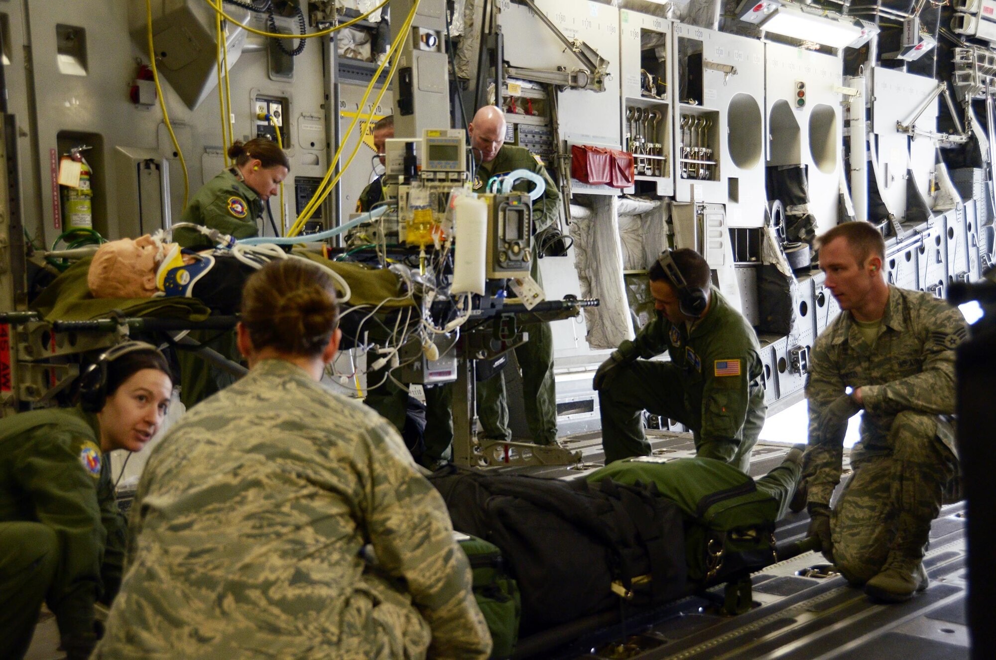 Airmen from the 445th Aeromedical Staging Squadron and 445th Aeromedical Evacuation Squadron lift a "patient" onto a litter stanchion while on board a 445th Airlift Wing C-17 Globemaster III, April 1, 2017. The two units worked together during a training exercise to provide care to notional patients. (U.S. Air Force photo/Staff Sgt. Joel McCullough)