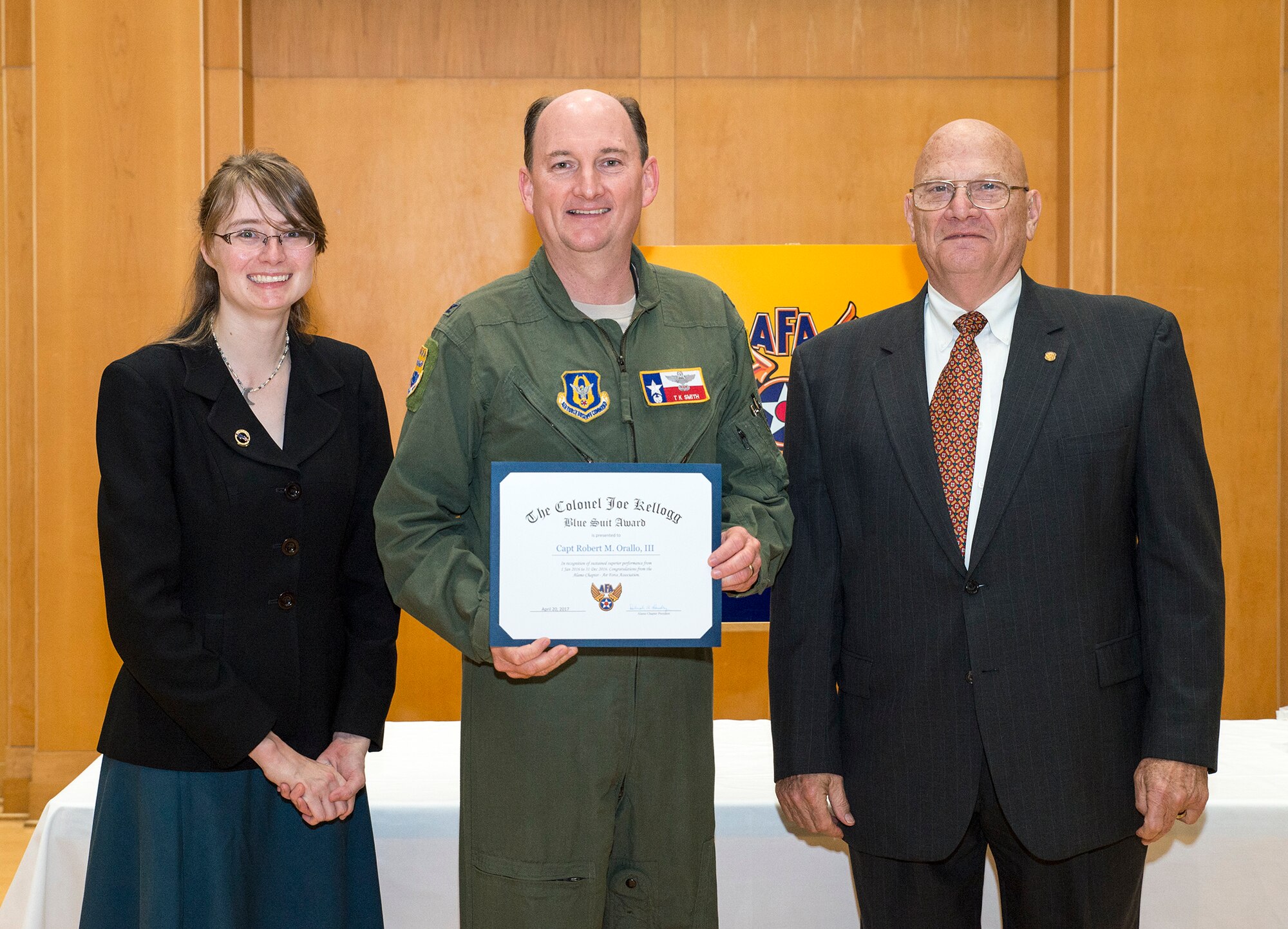 Col. Thomas K. Smith, Jr. 433rd Airlift Wing commander, accepts the Blue Suit Award for Capt. Robert Orallo III, 26th Aerial Port Squadron ramp flight commander, at the Alamo Chapter Air Force Association luncheon April 20, 2017 at the Monsignor Martin Family Center in San Antonio, Texas. 