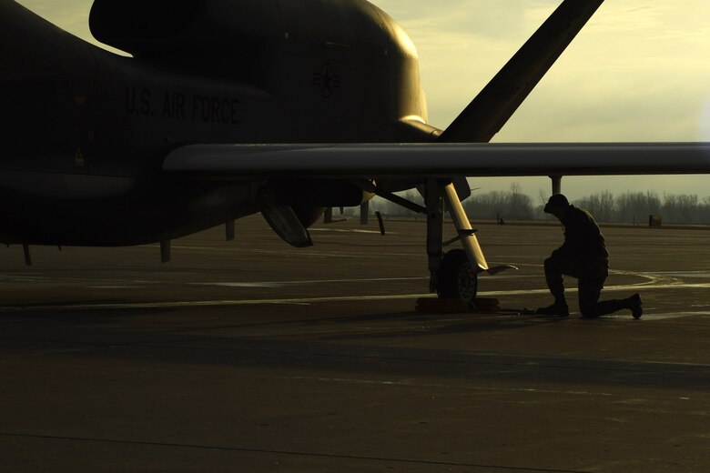 An Airman with the 69th Maintenance Squadron kneels beneath the wing of an RQ-4 Global Hawk March 25, 2017, on Grand Forks Air Force Base, N.D. Airmen with the 69th MXS performed the first Air Force-led Mobile Automated Scanner scan on this aircraft, which allowed it to continue its part in supporting the combatant commands. (U.S. Air Force photo by Senior Airman Ryan Sparks)