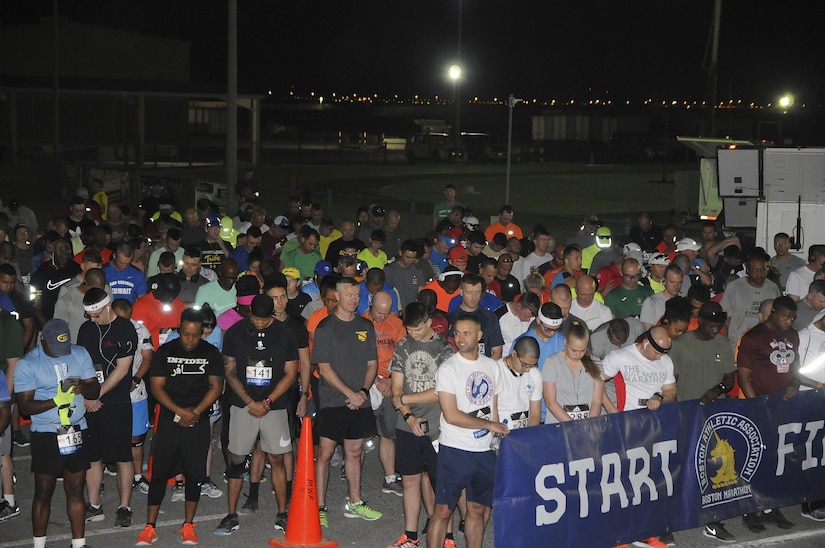 Personnel from throughout the U.S. Army Central area of operations hold the Boston Athletic Association ‘Start Finish’ banner and bow their heads in prayer before the start of the Boston Marathon Shadow Run, April 17, Camp Arifjan, Kuwait. This race shadowed the 121st Boston Marathon, but was the first for Camp Arifjan, and gave deployed personnel an opportunity to participate in the well-known marathon. (U.S. Army photo by Sgt. Kimberly Browne, USARCENT Public Affairs)