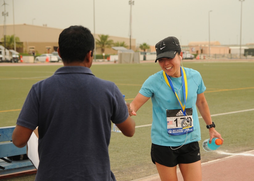 Maj. Jeannie Huh, a Soldier with the 31st Combat Support Hospital, a bottle of water from a volunteer after placing first in the women’s division with a time of three hours, 15 minutes, 33 seconds, in Camp Arifjan’s first Boston Marathon Shadow Run, April 17, Camp Arifjan, Kuwait. This race shadowed the 121st Boston Marathon, and gave deployed personnel an opportunity to run in the famous marathon. More than 300 people participated in the shadow run.  (U.S. Army photo by Sgt. Kimberly Browne, USARCENT Public Affairs)