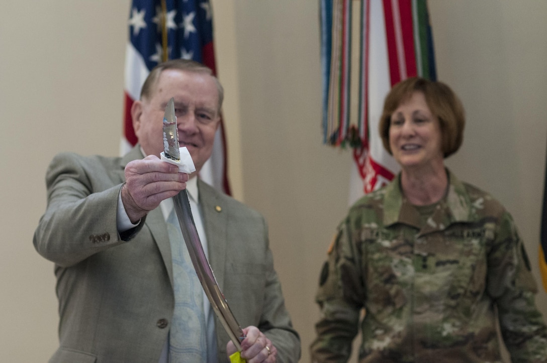 Rexford Davis, with the U.S. Army Reserve Command G-3/5/7, wipes cake off the ceremonial saber as Maj. Gen. Megan P. Tatu, U.S. Army Reserve Command chief of staff, looks on at the USARC headquarters, April 21, 2017, at Fort Bragg, N.C. Soldiers and civilians at the headquarters celebrated the 109th anniversary of the of the U.S. Army Reserve. Created in 1908 as the Medical Reserve Corps, America's Army Reserve of today has transformed into a capable, combat-ready, and lethal Federal reserve force in support of the Army at home and abroad. (U.S. Army Reserve photo by Timothy L. Hale)(Released)