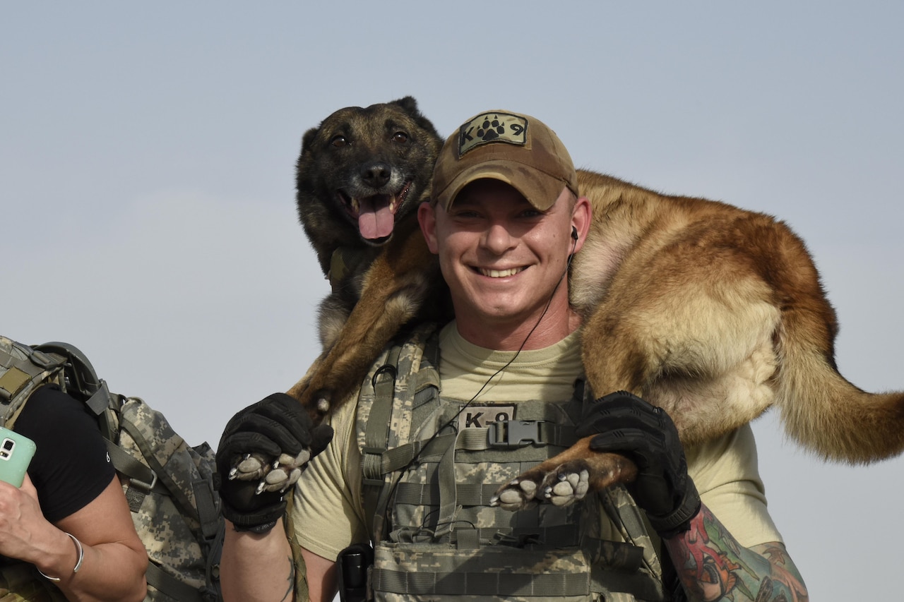 U.S. Air Force Staff Sgt. Christopher Kench, a military working dog handler with the 379th Expeditionary Security Forces Squadron, carries his military working dog Beta towards the end of a three-mile ruck at Al Udeid Air Base, Qatar, April 20, 2017. The carrying of one’s military working dog across the final stretch was meant to be symbolic of teamwork during the commemoration ruck march. (U.S. Air Force photo by Senior Airman Cynthia A. Innocenti)