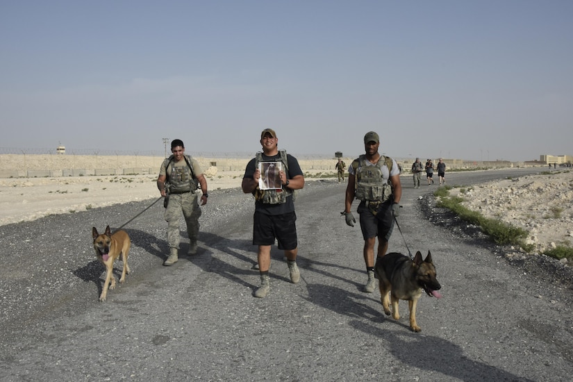 U.S. Air Force Staff Sgt. Amadio Apilado, military working dog trainer with the 379th Expeditionary Security Forces Squadron holds up a photo of Sarge, a fallen U.S. Air Force military working dog that served in the Vietnam war, during a three-mile ruck at Al Udeid Air Base, Qatar, April 20, 2017. Apilado wanted to honor Sarge during the ruck because it was a commemoration themed march to honor all fallen military working dogs and handlers. (U.S. Air Force photo by Senior Airman Cynthia A. Innocenti)