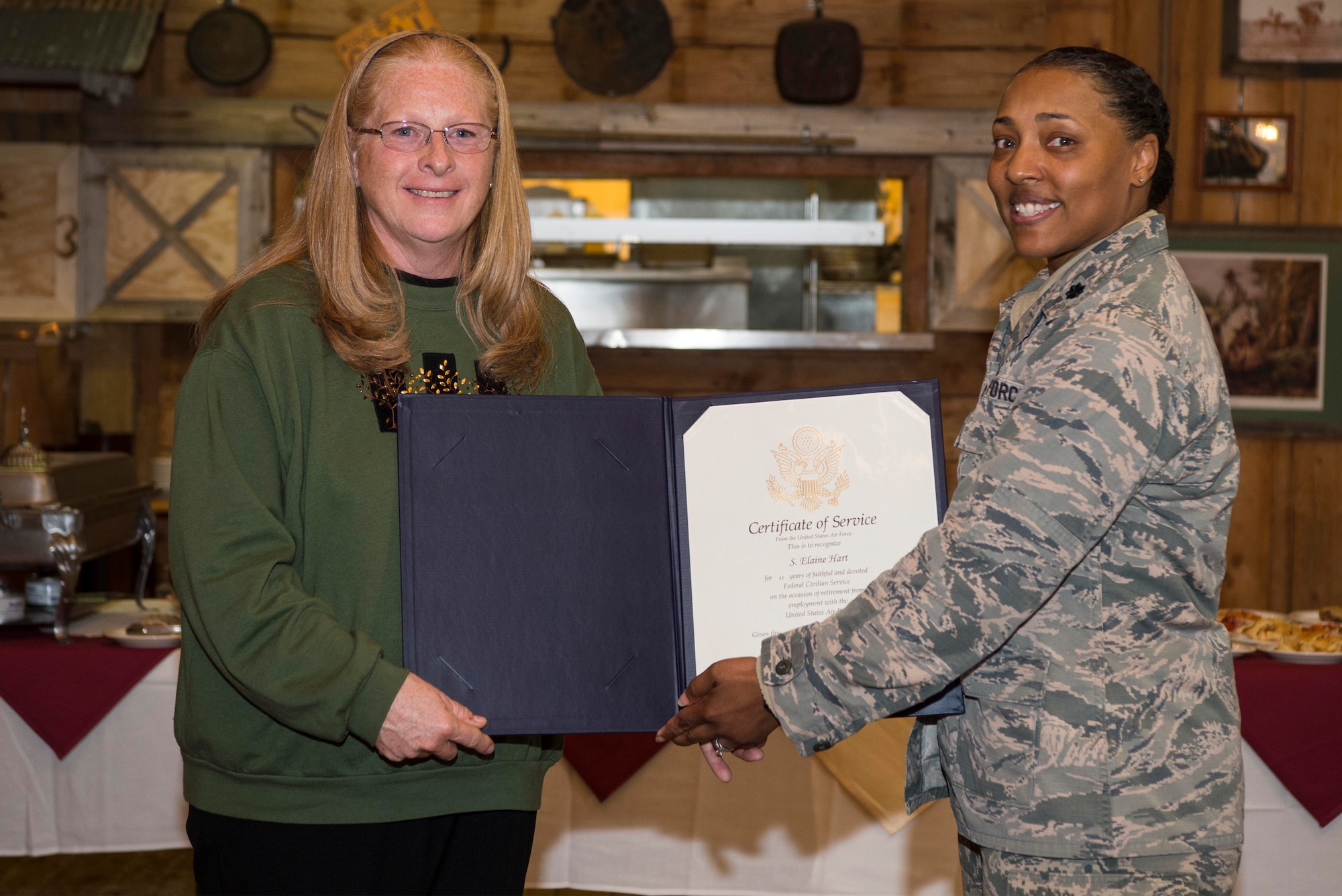 Lt. Col. Tiaundra Moncrief, 90th Missile Wing Legal Office staff judge advocate, presents Elaine Hart, 90th MW Legal Office recorder, with a Certificate of Service during her retirement ceremony at F.E. Warren Air Force Base, Wyo., April 21, 2017. The Certificate of Service is to recognize Hart’s 45 years of federal civilian service. (U.S. Air Force photo by Staff Sgt. Christopher Ruano)