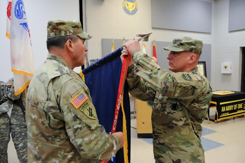 Maj. Gen. Troy D. Kok, commanding general of the U.S. Army Reserve’s 99th Regional Support Command (right), and Command Sgt. Maj. Al Almeida, 99th RSC command sergeant major, affix the Army Superior Unit Award streamer to the 99th RSC Colors during a ceremony April 21 at the command’s headquarters on Joint Base McGuire-Dix-Lakehurst, New Jersey. The 99th RSC received the award for providing aid and assistance from October 2012 to April 2013 to communities in New York City that were devastated by Superstorm Sandy.