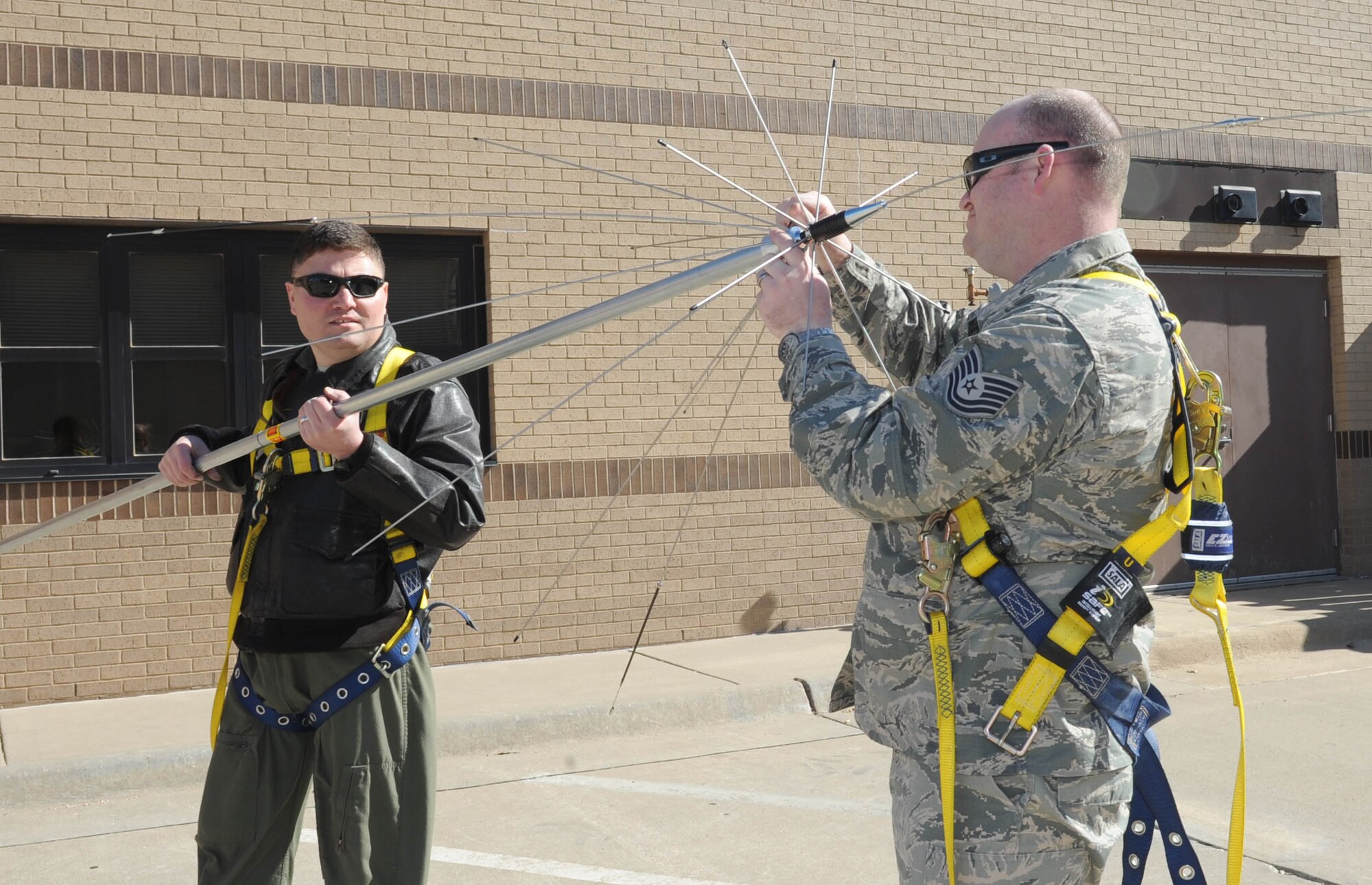 Master Sgt. Bartek Bachleda, left, 22nd Air Refueling Wing Plans and Programs superintendent, and Tech. Sgt. Clayton Allen, 22nd ARW XP NCO in charge, make an adjustment on an antenna before mounting it to a 22nd Logistics Readiness Squadron building, April 6, 2017, at McConnell Air Force Base, Kan. The antenna, along with a scanner radio, allows 22nd LRS vehicle dispatch to respond almost instantly to aircrew requests for transportation. (U.S. Air Force photo/Senior Airman Tara Fadenrecht)  