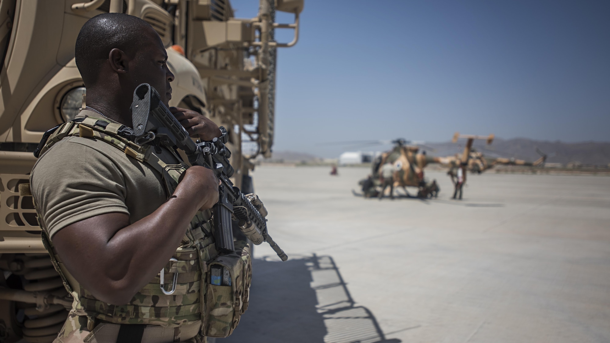 Senior Airman Micheal Thomas, 738th Air Expeditionary Advisory Group guardian angel, provides armed overwatch for contractors and air advisors performing maintenance on an Afghan Air Force MD-530 Light Attack Helicopter, April 16, 2017, at Kandahar Air Wing, Afghanistan. Thomas is deployed with other Citizen Airmen from the 507th Security Forces Squadron, Tinker Air Force Base, Okla. (U.S. Air Force photo/Staff Sgt. Katherine Spessa)