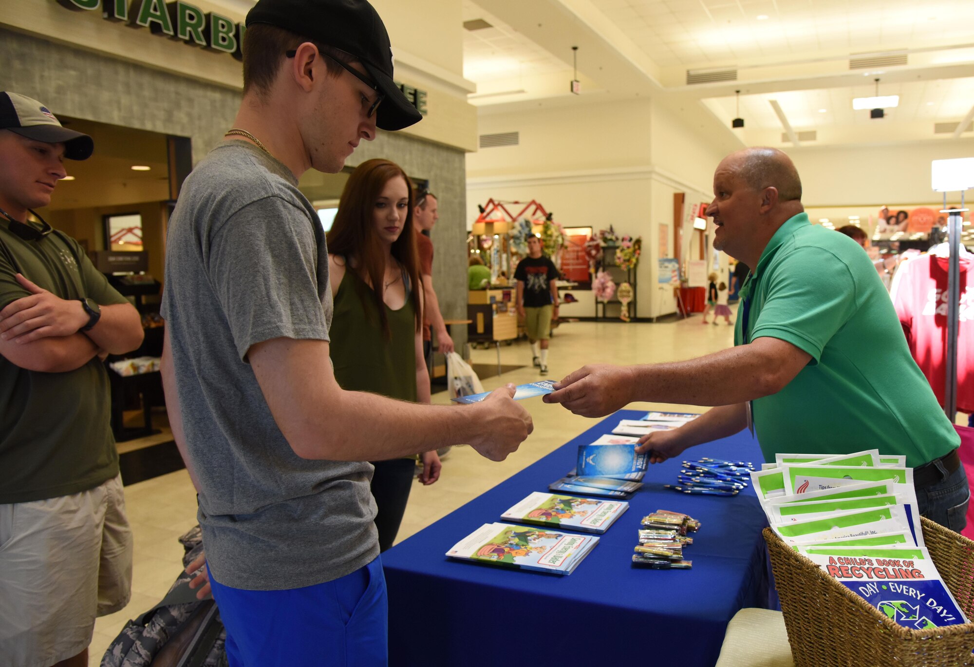 Bruce Groves, Base Operations Support energy manager, passes out recycling pamphlets in the base exchange April 21, 2017, on Keesler Air Force Base, Miss. The base operations support energy program and environmental office staffs set-up a booth with hand-outs and reading material about recycling and environmental sustainability for Keesler personnel in recognition of Earth Day. (U.S. Air Force photo by Kemberly Groue)