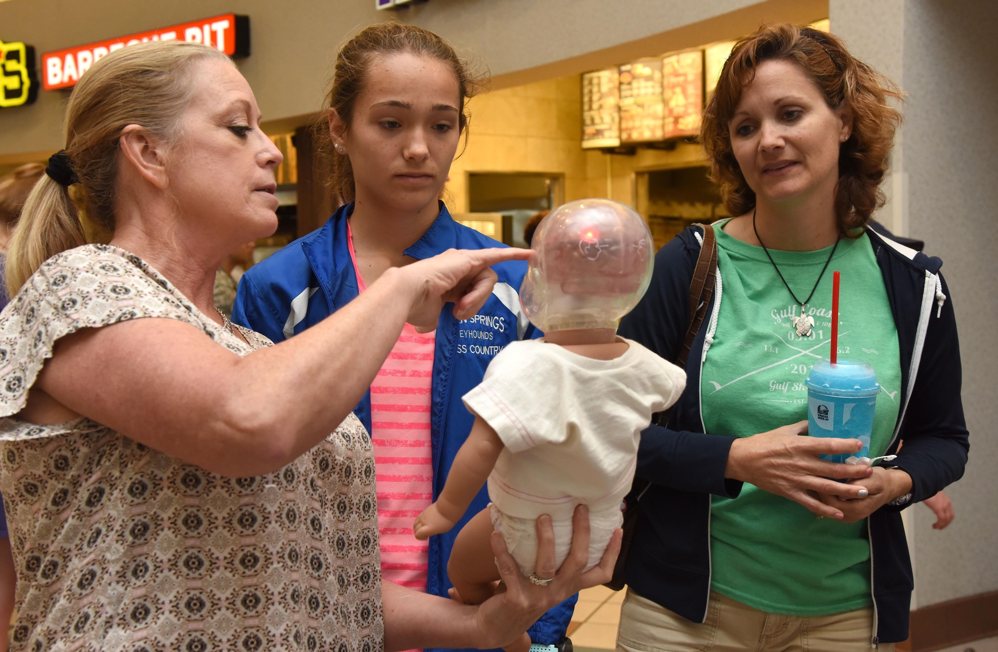 Paula Spooner, 81st Medical Operations Squadron family advocacy outreach manager, provides a shaken baby syndrome simulation to Isabelle and Lori Wheeler in the base exchange April 21, 2017, on Keesler Air Force Base, Miss. The family advocacy staff manned a booth with hand-outs and reading material about child abuse prevention for Keesler personnel in recognition of Child Abuse Prevention Month. (U.S. Air Force photo by Kemberly Groue)
