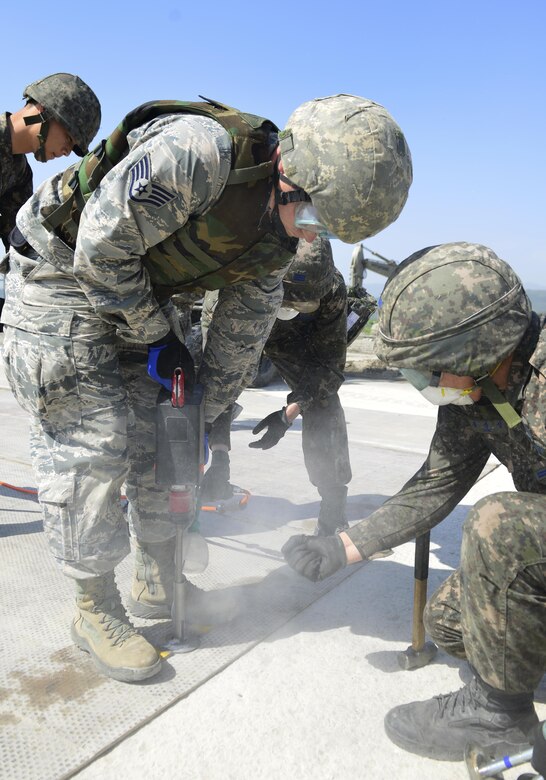 U.S. and Republic of Korea Airmen secure the rapid-runway repair fiberglass mat during the U.S./ROK Combined Airfield Damage Repair Exercise at Daegu Air Base, April 19, 2017. After the five day exercise, the two forces were more than ready to repair airfields together, ensuring the critical function of safely launching and recovering aircraft. (U.S. Air Force photo by Staff Sgt. Alex Fox Echols III)