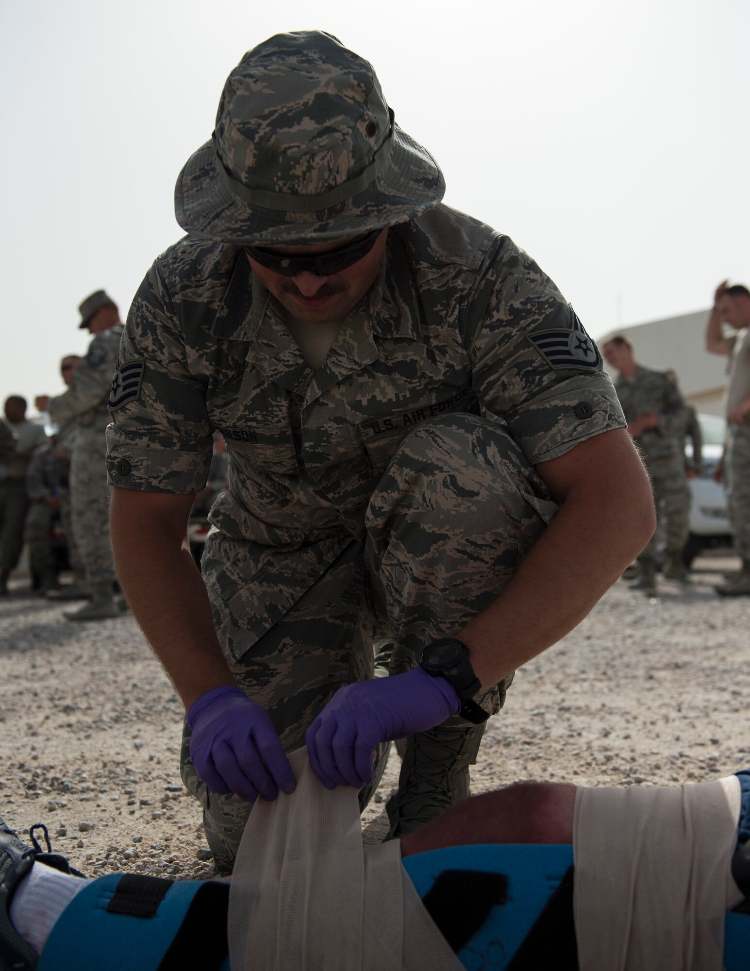 U.S. Air Force Staff Sgt. Jared Johnson, 379th Expeditionary Medical Group, places a bandage onto a role players leg at Al Udeid Air Base, Qatar, April 17, 2017. The active shooter exercise tested the skills and abilities of Airmen to work with other units in in order to gain a better understanding of each other’s roles in the event of a real-world situation.   (U.S. Air Force photo by Tech. Sgt. Amy M. Lovgren)