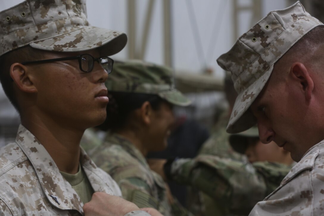 U.S. Marine Corps Staff Sgt. Brent Morris, the data chief with Special Purpose Marine Air-Ground Task Force-Crisis Response-Central Command, pins the air assault badge to the chest of Lance Cpl. Davy Yang, a cyber network operator with SPMAGTF-CR-CC, during a recognition ceremony while forward deployed in the Middle East, April 14, 2017. The air assault course is designed to teach soldiers skills such as rappelling techniques and sling load procedures. SPMAGTF-CR-CC is a well-trained crisis response unit that has the ability to project combat power over vast distances using organic aviation, logistical, and ground combat assets.(U.S. Marine Corps photo by Lance Cpl. Joshua McAlpine)