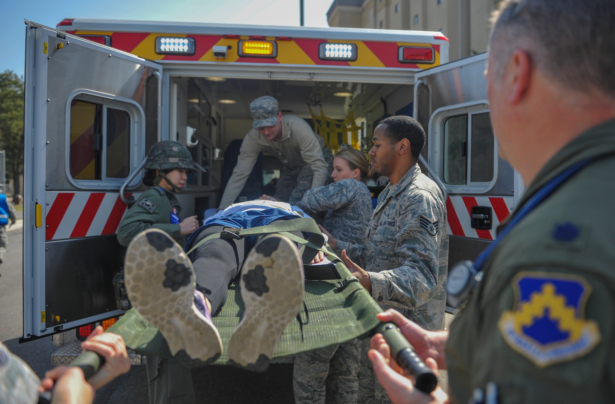 United States Air Force members assigned to the 8th Medical Group and Republic of Korea Air Force medical airmen work together to lift an airman into an ambulance during a mass casualty exercise at Kunsan Air Base, Republic of Korea, April 19, 2017. U.S. and ROK airmen conducted the training to evaluate their ability to communicate and operate through a MASCAL situation. (U.S. Air Force photo by Senior Airman Colville McFee/Released)