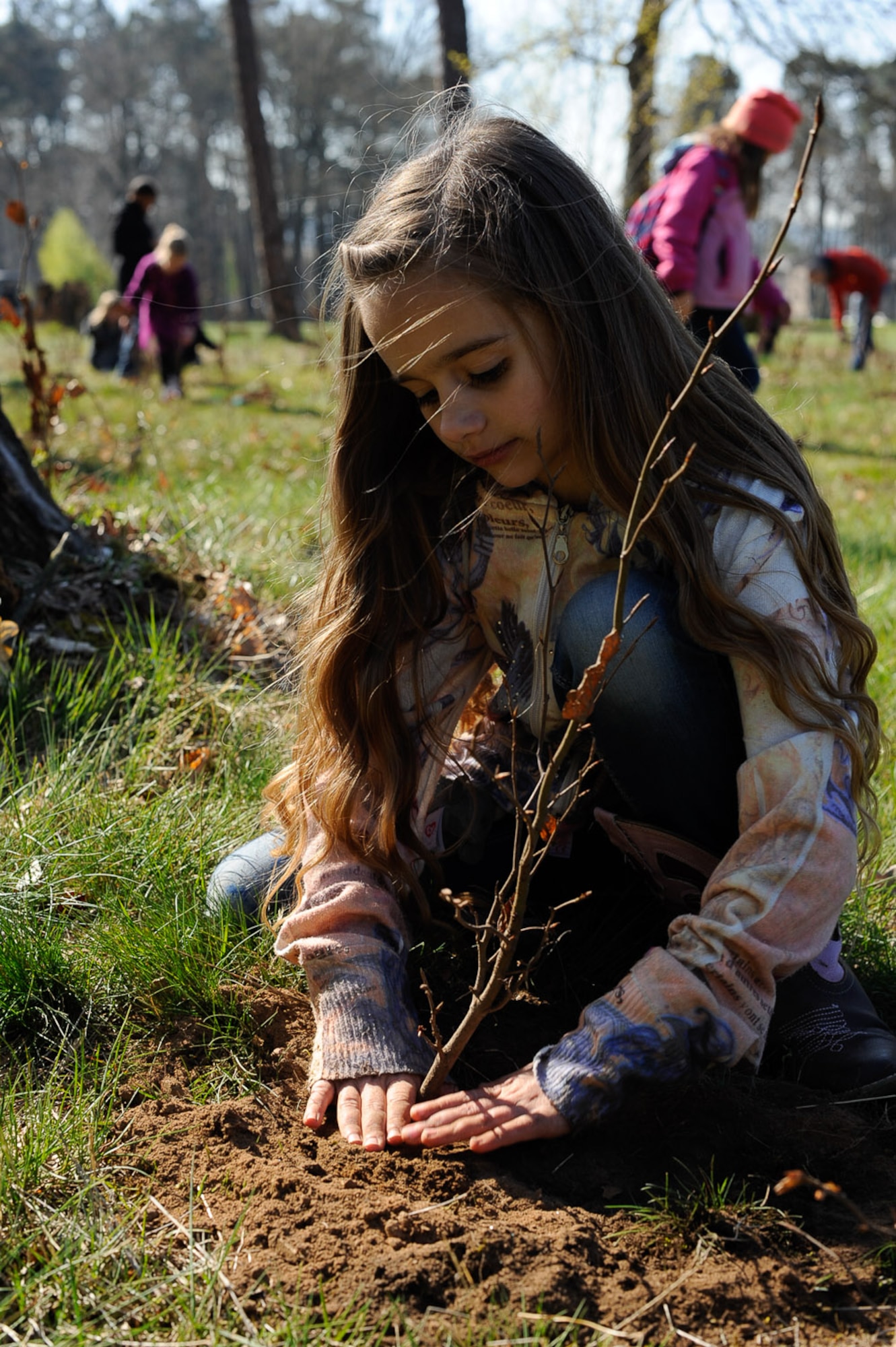 Celeste Bronson, daughter of Maj. Hyrum Bronson, United States Transportation Command flight surgeon, presses dirt into a planted tree on Ramstein Air Base, Germany, April 21, 2017. Kaiserslautern Military Community students, 86th Civil Engineer Group Airmen and federal forest departments celebrated Earth Day by planting more than 1,500 trees on base. (U.S. Air Force photo by Airman 1st Class Savannah L. Waters)