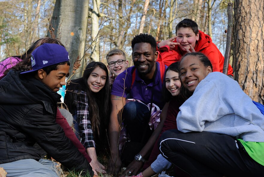 Ahmaed Cephus, Ramstein Middle School Advancement via Individual Determination (AVID) instructor, poses for a photo as he plants a tree with his students on Ramstein Air Base, Germany, April 21, 2017. Students celebrated Earth Day demonstrating support for environmental protection by planting trees. (U.S. Air Force photo by Airman 1st Class Savannah L. Waters)