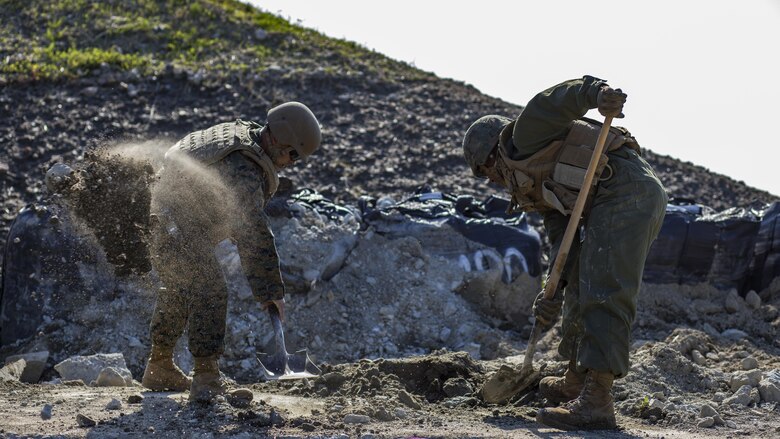 U.S. Marine Corps Gunnery Sgt. Myron Sato, left, the combat engineer staff-non-commissioned-officer-in-charge for Marine Wing Support Squadron 171, and Pfc. Jason Taylor, right a combat engineer with MWSS-171, shovel dirt and mud during airfield damage and repair training at Marine Corps Air Station Iwakuni, Japan, April 19, 2017. The ADR training required Marines to utilize their skill set to tactically and proficiently fix any anomalies to a simulated damaged airfield. The training focused on becoming more efficient in situations that may require Marines to act in real-world scenarios to maintain the tempo of aircraft operations. 