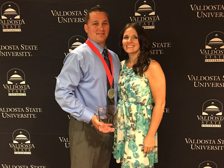 Staff Sgt. Joshua Dunn, 23d Component Maintenance Squadron aerospace propulsion craftsman, poses with his wife, Brentnie, as he holds the Military Hero Award during the American Red Cross of South Georgia Hero Awards, March 27, 2017, in Valdosta, Ga. On Feb. 3, Dunn utilized his Self-Aid & Buddy Care military training to ensure safety at the scene of a car accident scene. by blocking oncoming traffic and assessing the victim’s ailments until paramedics arrived. (Courtesy photo)