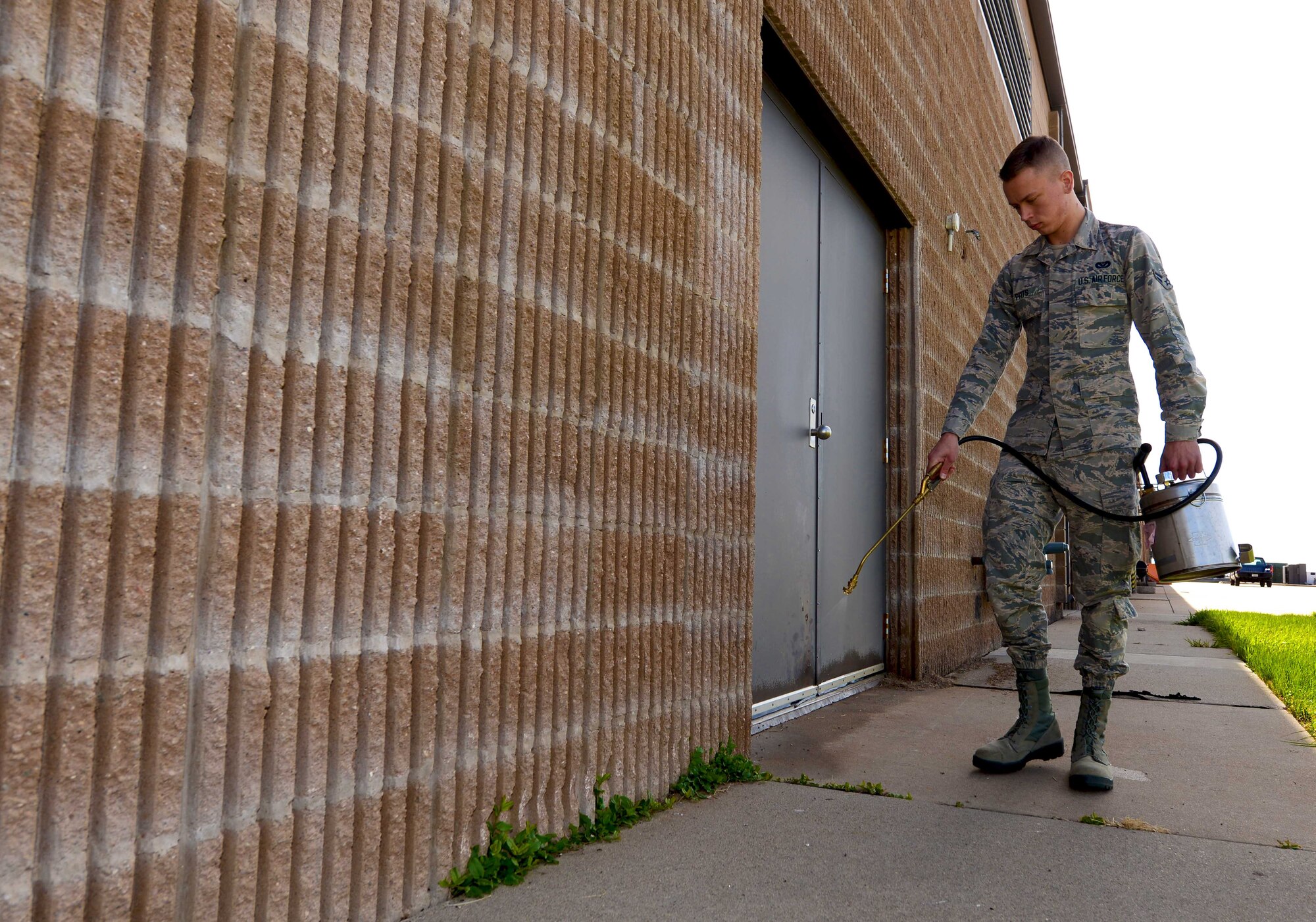 Airman 1st Class David Pitts, a pest management apprentice assigned to the 28th Civil Engineer Squadron, sprays pesticide along the backside of the 28th Maintenance Squadron at Ellsworth Air Force Base, S.D., April 7, 2017. Pest management utilize tools such as mouse traps, live traps, bird, and various sprayers to prevent pests from nesting on base. (U.S. Air Force photo by Airman 1st Class Donald C. Knechtel)