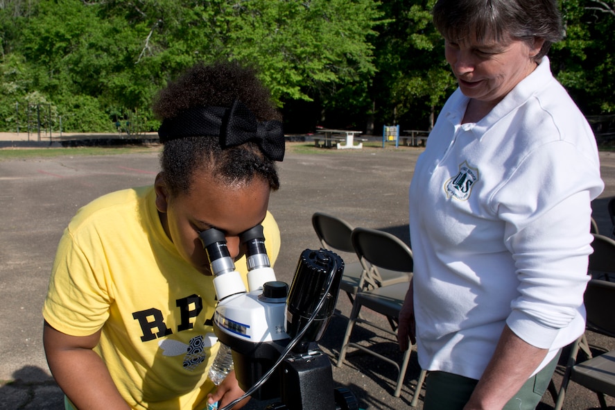 Susan L. Hooks, forest botanist, Ouachita and Ozark-St. Francis National Forests, assists a middle-school student from the Flightline Academy Charter School exam pollen samples at the Arnold Drive Elementary School Earth Day Expo April 20, 2017, at Little Rock Air Force Base, Ark. President Theodore Roosevelt established The Arkansas National Forest on December 18, 1907, and it is the oldest national forest in the South. On April 29, 1926, the forest was renamed as the Ouachita National Forest. (U.S. Air Force photo by Master Sgt. Jeff Walston/Released)